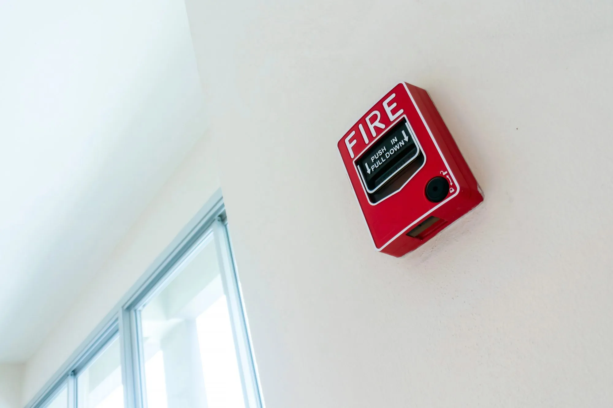 Red commercial fire alarm pull station mounted on a wall