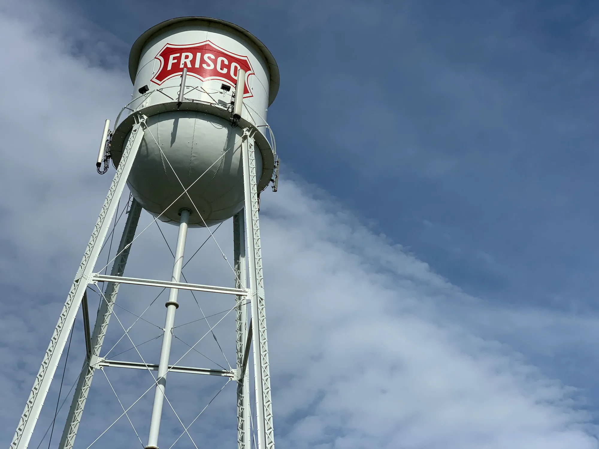 The Frisco water tower with the red Frisco shield against a blue sky