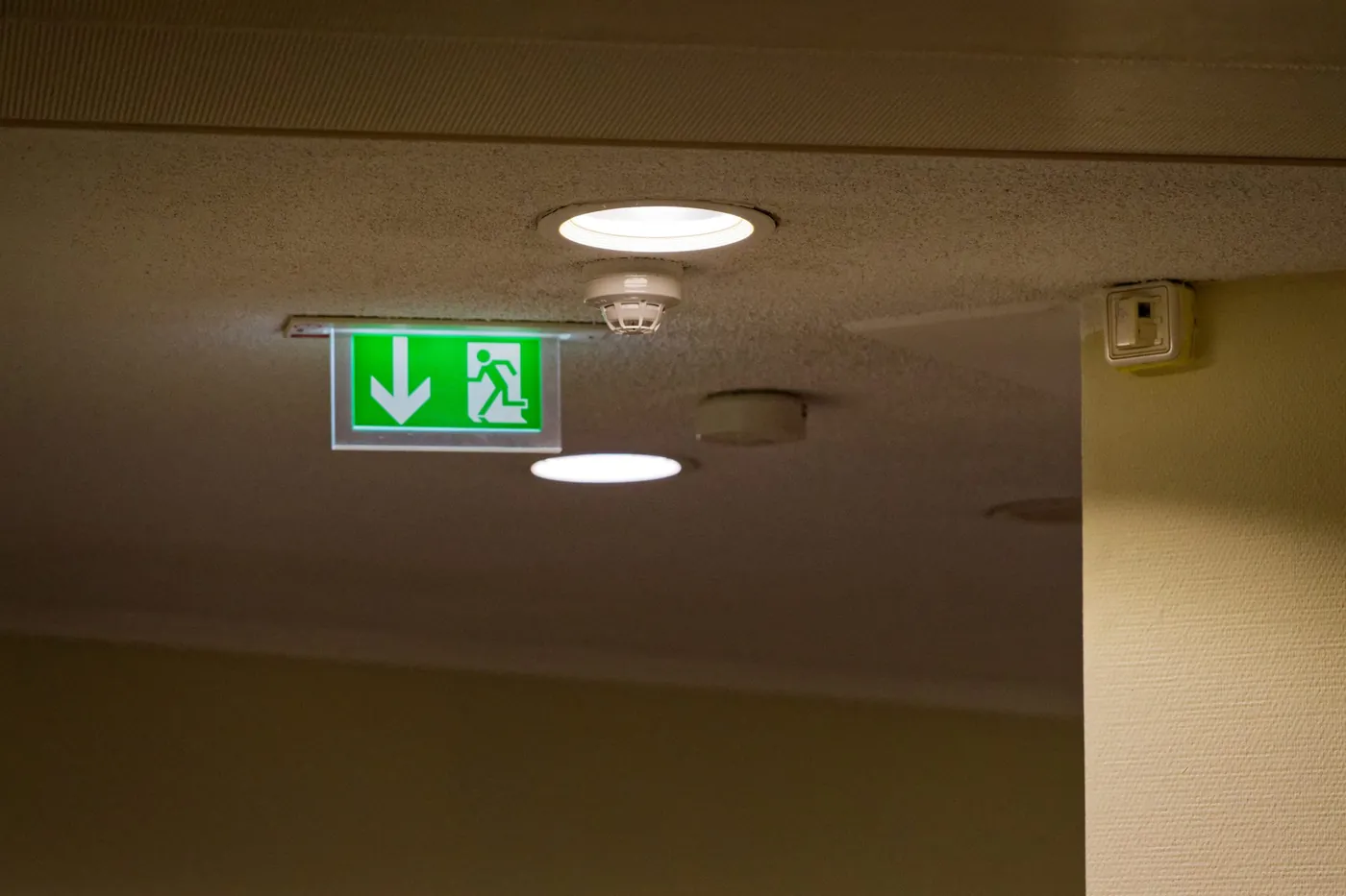 Illuminated emergency exit sign and ceiling smoke detector in a commercial building